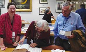 Photo of people in the library's special collections viewing a book from the collection.