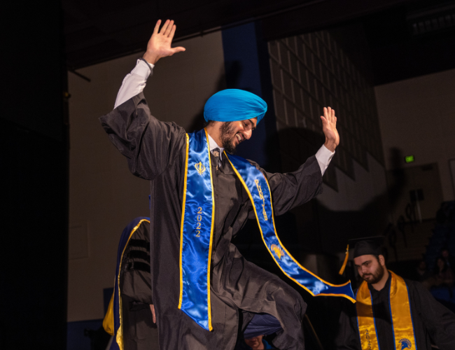 South Asians in Silicon Valley Exhibit. Photo of student dancing on stage during commencement. 